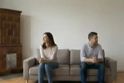 Krisenberatung bei Beziehungsproblemen Ein unglückliches Paar sitzt abgewendet auf dem Sofa während einer Beziehungskrise oder Paarberatung